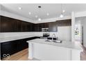 Modern kitchen with dark cabinets, a marble countertop island, and stainless steel appliances at 385 N Post Oak Dr, Mooresville, IN 46158