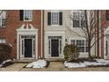 Townhome entrance with brick facade, black doors, and winter landscaping at 2342 The Springs Dr, Indianapolis, IN 46260