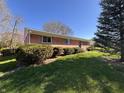 Well-maintained brick house featuring mature landscaping and an expansive green lawn at 6628 E Michigan St, Indianapolis, IN 46219