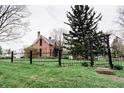 Classic red brick home with black trim and fencing, surrounded by a lush green lawn and mature trees at 301 Lowry St, Jamestown, IN 46147