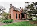 Quaint red brick home showcases a dark trim, inviting architecture, and a well-manicured green lawn at 301 Lowry St, Jamestown, IN 46147