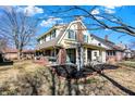 Angle view of the home's exterior showing brick accents, a covered porch, and lush landscaping at 5210 E Pleasant Run Parkway North Dr, Indianapolis, IN 46219