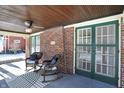Inviting front porch with rocking chairs, brick accents, a ceiling fan, and a bead-board ceiling at 5210 E Pleasant Run Parkway North Dr, Indianapolis, IN 46219