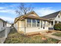 Well-maintained home with sunroom, framed by a neat yard and chain link fence at 1028 Albany St, Indianapolis, IN 46203