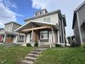 Attractive two-story duplex featuring a covered front porch and tidy landscaping at 2033 Carrollton Ave, Indianapolis, IN 46202