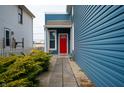 Cozy side entrance of a home with a vibrant red door, complemented by lush greenery at 1130 S Senate Ave, Indianapolis, IN 46225