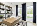 Modern home office with wood desk, shelves, and large windows at 14569 Hanford Ln, Carmel, IN 46032