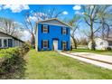 Two-story blue home featuring black shutters, a manicured lawn, and a concrete driveway at 3264 Orchard Ave, Indianapolis, IN 46218