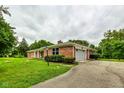 Brick ranch house with a gray garage door and landscaped yard at 4657 E 62Nd St, Indianapolis, IN 46220