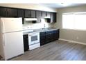 Dark kitchen cabinets, white appliances, and grey laminate flooring at 9903 E 17Th St, Indianapolis, IN 46229