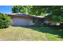 Ranch house with a gray garage door and mature trees at 1165 Wood Ct, Indianapolis, IN 46227