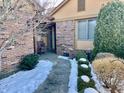 Brick front entry with walkway, landscaping, and snow at 131 E Ravenswood Dr # 18-D, Anderson, IN 46012