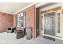Brick front porch with two wicker chairs and decorative metal angel at 15131 Newburyport Dr, Fishers, IN 46040