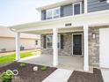 Welcoming covered front porch with stone accents, white pillars, and a stylish black front door at 7541 Big Bend Blvd, Camby, IN 46113