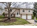 Split-level home with neutral siding, white trim, an attached garage, and a well-kept front yard at 9229 Thrushwood Ln, Indianapolis, IN 46250