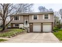 Split-level home featuring neutral siding, a two-car garage, and a well-maintained front lawn at 9229 Thrushwood Ln, Indianapolis, IN 46250