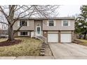 Charming split-level home featuring a two-car garage and a welcoming front entrance with stairs at 9229 Thrushwood Ln, Indianapolis, IN 46250