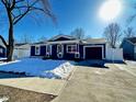 Newly renovated blue house with snow covered lawn and driveway at 9519 Meadowlark Dr, Indianapolis, IN 46235