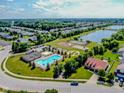 Aerial view of community pool, clubhouse, tennis courts, and playground surrounded by lush landscaping and a serene lake at 10391 Butler Dr, Brownsburg, IN 46112