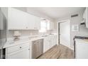 Bright kitchen featuring white cabinets, stainless steel appliances, and wood grain vinyl floors at 3017 Sherman St, Anderson, IN 46016