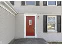 A close-up of a red front door with white trim and black shutters at 7721 Cambridge Dr, Fishers, IN 46038