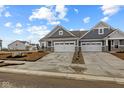 Attractive townhome with gray siding, stone accents, two-car garage, and professionally landscaped front yard at 16964 Cattle Hollow Ln, Noblesville, IN 46060