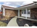 Inviting front porch with brick accents and landscaped garden beds at 2338 Malibu Ct, Anderson, IN 46012