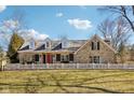 Charming stone home featuring a bright red door, dormer windows and a white picket fence at 7837 Dean Rd, Indianapolis, IN 46240