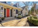 Inviting front entrance with a bright red door, stone facade, and a walkway surrounded by greenery at 7837 Dean Rd, Indianapolis, IN 46240