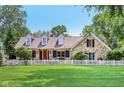 Beautiful stone home with a red front door, black shutters, and well-maintained lawn and landscaping at 7837 Dean Rd, Indianapolis, IN 46240