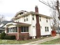 Side view of a traditional two-story home with a brick chimney, small deck, and a partially visible lawn at 917 E 34Th St, Indianapolis, IN 46205