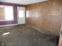 Living room with wood paneling and dirty carpet at 1300 W 13Th St, Muncie, IN 47302