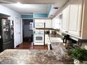 White kitchen with stainless steel appliances and wood floors at 3163 S 25 E, Shelbyville, IN 46176
