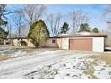 View of the home's garage, with a snow-covered yard in the foreground at 4820 E 70Th St, Indianapolis, IN 46220