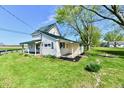 Inviting two-story home with a covered porch, green roof, and a spacious front yard at 4992 W 100 S, New Palestine, IN 46163