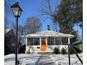 Charming single-story home featuring an orange front door and a screened in porch, complemented by snowy front yard at 5630 Winthrop Ave, Indianapolis, IN 46220