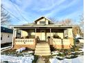 Tan house with front porch, steps, and small yard with snow at 808 S Burlington Dr, Muncie, IN 47302