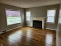 Bright living room with hardwood floors, a decorative fireplace, and natural light streaming through the windows at 3513 N Layman Ave, Indianapolis, IN 46218