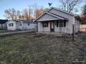 Adorable home with a covered porch, featuring black shutters and railings for a classic look, surrounded by a grassy yard at 3619 N Hawthorne Ln, Indianapolis, IN 46218