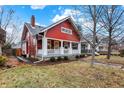 Side view of a red two-story home with a welcoming porch and manicured lawn at 4616 Carrollton Ave, Indianapolis, IN 46205