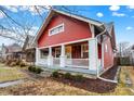 Charming red home with a welcoming front porch and manicured landscaping at 4616 Carrollton Ave, Indianapolis, IN 46205