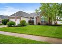 Attractive brick home showcasing a lush green lawn, mature tree, and an American flag in the front yard at 8535 Blue Marlin Dr, Indianapolis, IN 46239