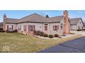 Tan brick ranch home with red shutters, landscaped lawn, and a private fenced backyard at 1088 Laurelwood Ln, Greenwood, IN 46142