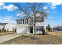 Two-story house with beige vinyl siding, white brick accents, and a two-car garage at 13195 Westwood Ln, Fishers, IN 46038
