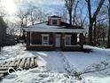 Brick home with front porch, snowy yard, and mature trees at 1459 W 33Rd St, Indianapolis, IN 46208