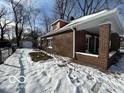 Brick home with side porch and detached garage, snowy yard at 1459 W 33Rd St, Indianapolis, IN 46208