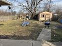 Large backyard with shed, wood fence, grass and concrete sidewalk leading to a grill at 4119 N Butler Ave, Indianapolis, IN 46226