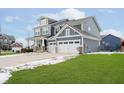 Side angle of charming two-story home featuring a three-car garage and impeccable curb appeal at 10214 Cloverbank Dr, Fishers, IN 46040