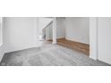 Upstairs hallway with neutral carpet, wood-style flooring, and a view of the white stairs and walls at 349 N Post Oak Dr, Mooresville, IN 46158
