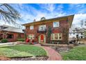 Inviting two-story brick home featuring a beautiful lawn, brick walkway, and charming front porch with red chairs at 43 W Hampton Dr, Indianapolis, IN 46208